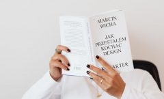 Anonymous female in white shirt with gold chain on neck reading interesting book covering face while sitting on black chair