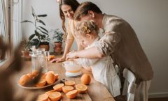 A family enjoys making fresh orange juice together in a warm and inviting kitchen setting.